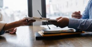 Twee zakenmensen wisselen documenten uit aan bureau